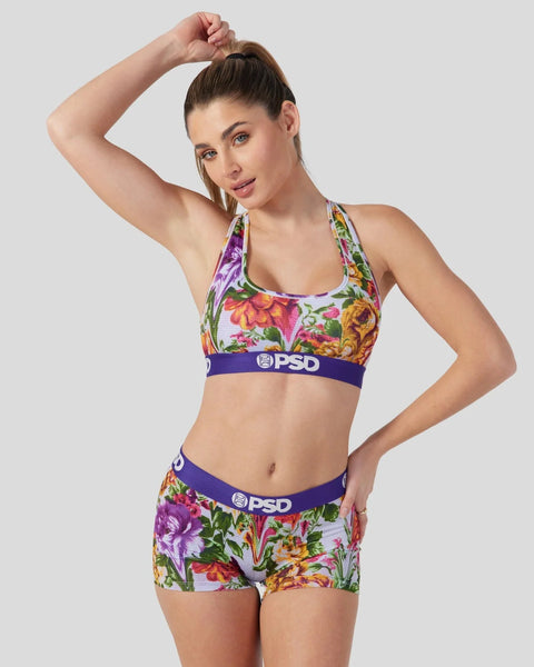 Woman wearing colorful floral print sports bra and matching shorts with purple PSD waistband.