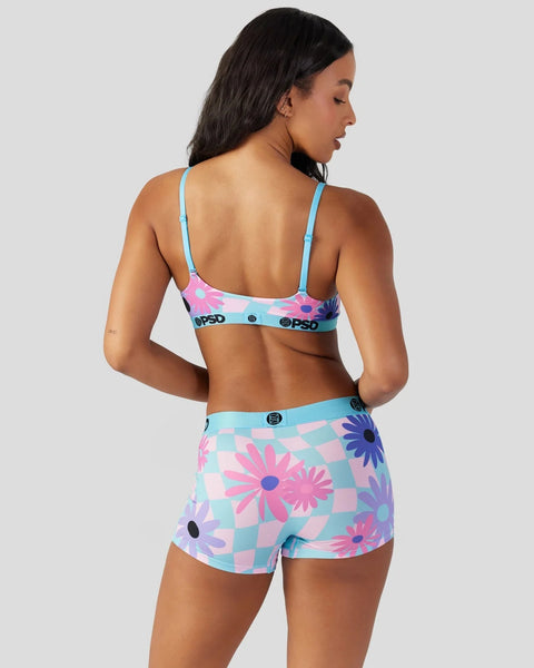 Woman wearing blue spaghetti strap bra and matching shorts with pink, purple, and blue floral checkered pattern.