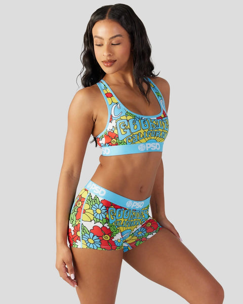 Woman wearing colorful floral print sports bra and shorts set with blue trim and text graphics.