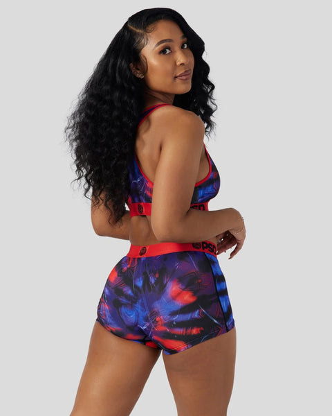 Woman wearing red and blue Miles Morales-themed sports bra and shorts with geometric print design.