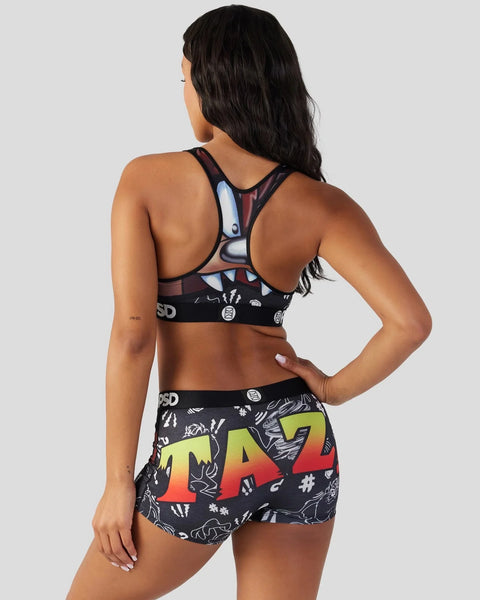 Woman wearing black sports bra and shorts with Looney Tunes Taz character graphics and yellow-to-red gradient text, back view