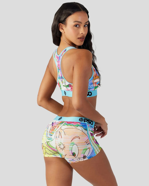 Woman wearing Looney Tunes-printed sports bra and shorts with colorful character graphics and PSD branding.