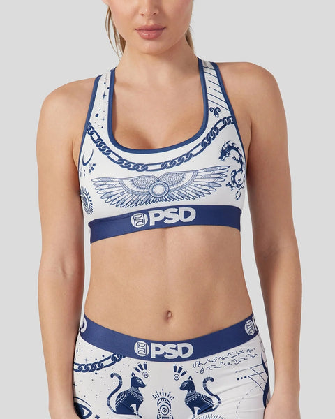 White and navy PSD sports bra with winged emblem and decorative tattoo-inspired graphics.