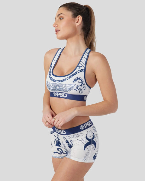 Woman wearing white and navy sports bra and shorts with blue tattoo-inspired graphic designs and PSD branding.