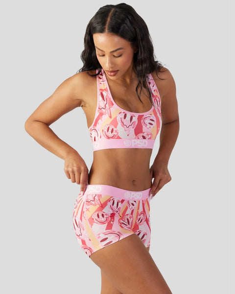 Pink sports bra and shorts set with red and coral smiley face print throughout.