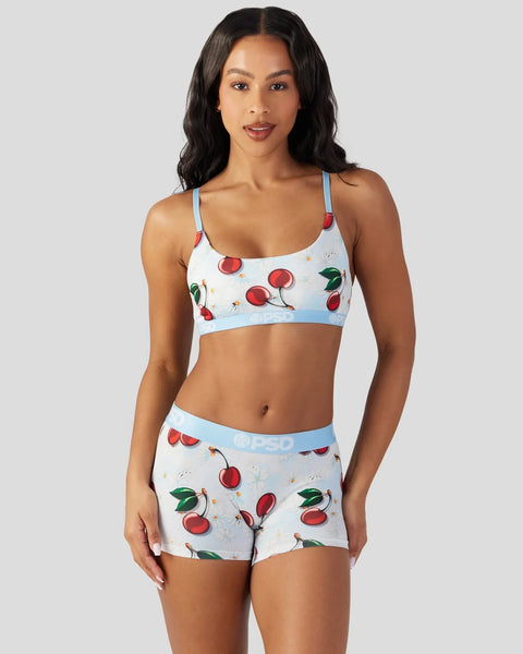 White sports bra and shorts set with red cherry print and light blue trim.