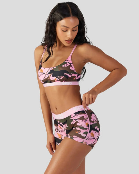 Woman wearing pink and black camouflage sports bra and matching shorts with mesh panels.