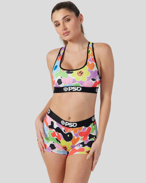 Woman wearing a colorful pop-art print sports bra and matching shorts set with black PSD waistbands.