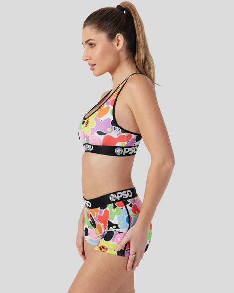 Woman wearing colorful multi-patterned sports bra and matching shorts with black PSD waistbands.