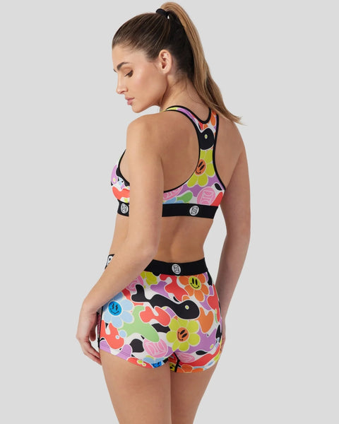 Colorful floral and smiley face print sports bra and shorts set with black trim and logo details.