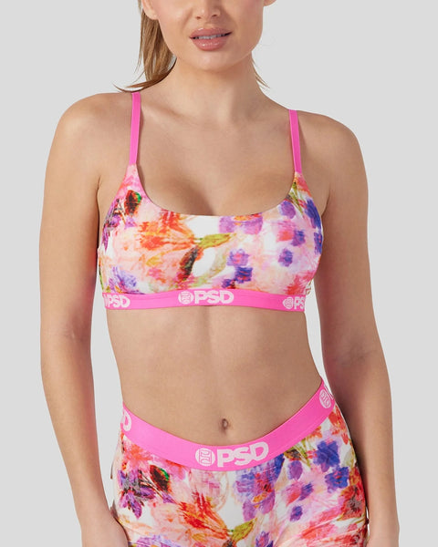 Woman wearing colorful floral print bikini with bright pink straps and PSD branding on waistband.