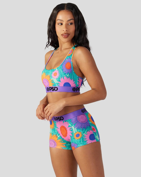 Colorful sunflower print sports bra and shorts set with purple waistbands and branding.