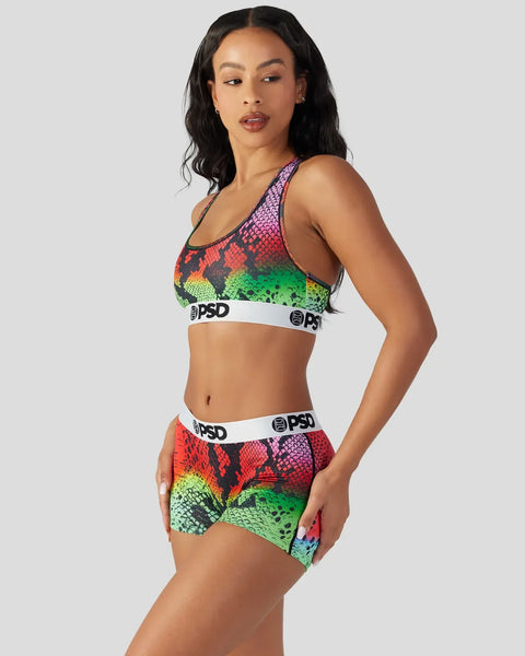 Woman wearing multicolored snake-scale patterned sports bra and shorts with white PSD waistbands.