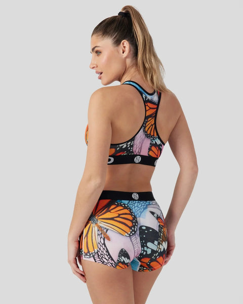 Woman wearing colorful butterfly-print sports bra and shorts set with orange, blue, and black pattern.