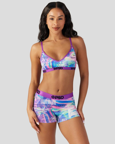 Woman wearing purple PSD sports bra and matching shorts with colorful digital print pattern.