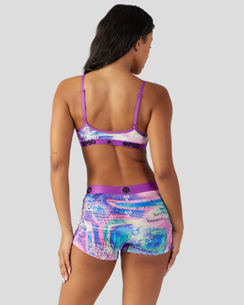 Woman wearing purple sports bra and colorful digital-print shorts with matching waistband, shown from behind.