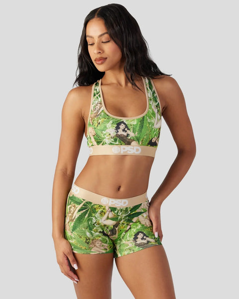 Woman wearing green and cream patterned sports bra and matching shorts with retro floral design.