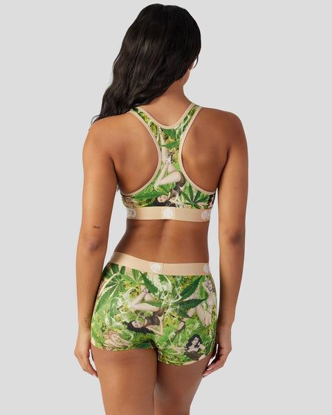 Woman wearing green leaf-print sports bra and matching shorts with cream-colored trim bands.