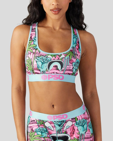 Women's sports bra with multicolor tropical and graphic print design, light blue waistband with branding.