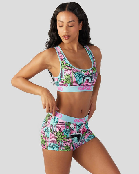 Woman wearing colorful floral print sports bra and matching shorts with turquoise elastic bands.