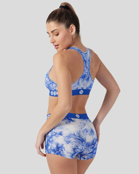 Woman wearing blue and white bandana-patterned sports bra and matching shorts, shown from back angle.