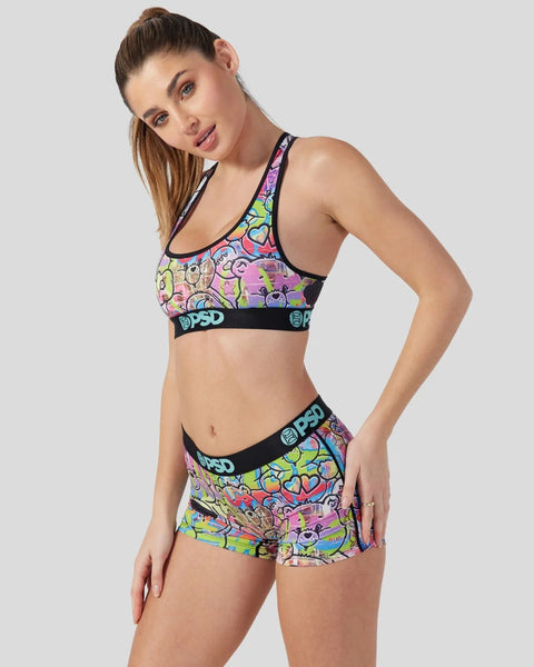 Woman wearing multicolored Care Bears-patterned sports bra and shorts set with black PSD waistbands.