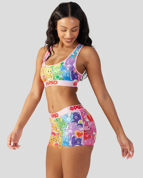 Woman wearing Care Bears rainbow sports bra and shorts with colorful bear characters and white elastic bands.