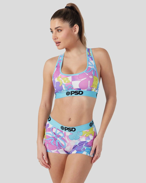 Woman wearing neon colorful patterned sports bra and matching shorts with blue waistband trim.