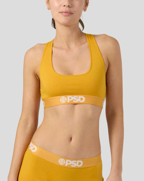 Woman wearing a mango yellow racerback sports bra with PSD branding and matching yellow briefs with elastic waistband.