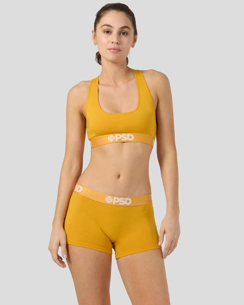 Woman wearing mango-yellow racerback sports bra and matching shorts with PSD waistband.