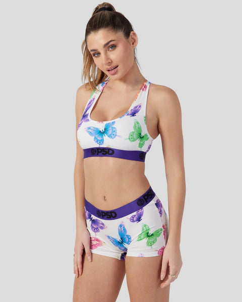 White sports bra and shorts set with colorful butterfly print and purple branded waistband.