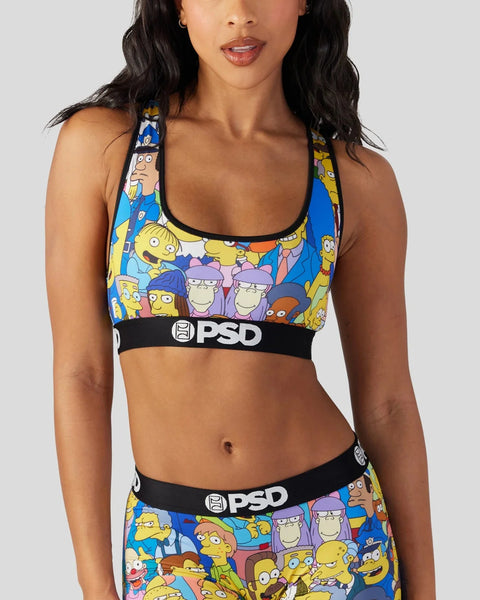 Woman wearing a blue sports bra and matching shorts with colorful Simpsons character print and black PSD waistbands.