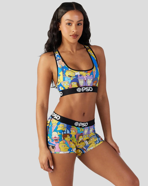 Women's sports bra and shorts set with Simpsons characters on blue and yellow background, black PSD branding.