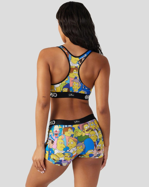 Woman wearing a colorful Simpsons character print sports bra and shorts set with blue and multicolored panels.