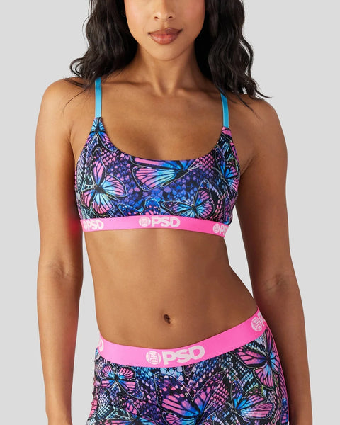 Sports bra with blue straps and colorful butterfly print on dark background, pink elastic waistband with branding.