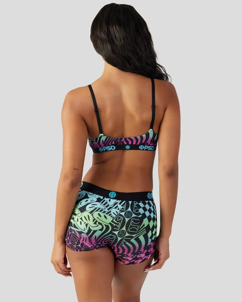 Woman wearing black spaghetti strap bra and matching shorts with multicolored neon abstract and geometric patterns.