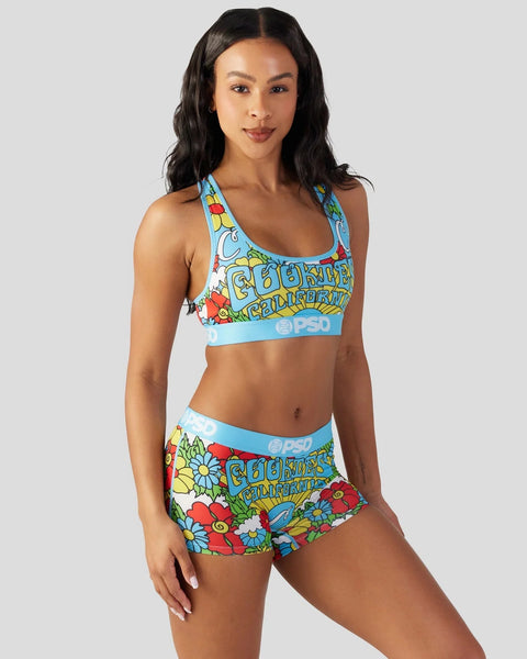 Woman wearing a colorful floral print sports bra and matching shorts with blue trim and branding.