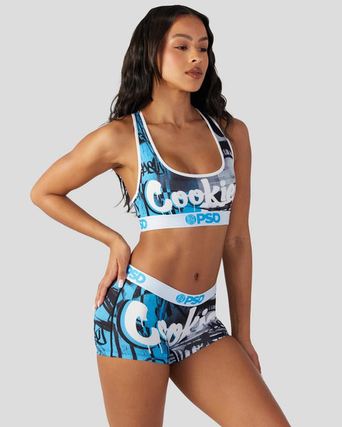 Woman wearing blue and black Cookies brand sports bra and matching shorts with white trim and PSD branding.