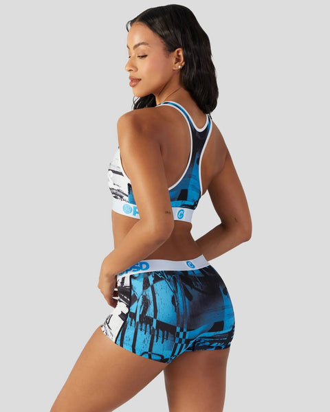 Woman wearing blue and white sports bra and matching patterned shorts with geometric design.