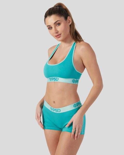 Jade green sports bra and shorts set with white trim and branded waistband, displayed on model.