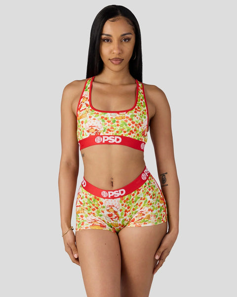 Woman wearing strawberry-patterned sports bra and shorts set with red trim and PSD branding.