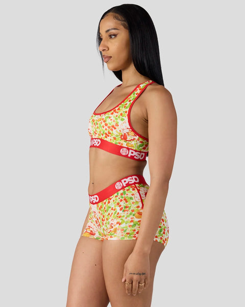 Woman wearing strawberry print sports bra and shorts set with red trim and branded waistband.