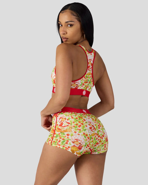 Woman wearing a red and multicolor strawberry-printed sports bra and matching shorts set with open back design.