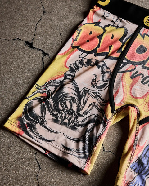 Graphic t-shirt with black scorpion illustration and pink-yellow abstract faces on cream and yellow fabric panels.