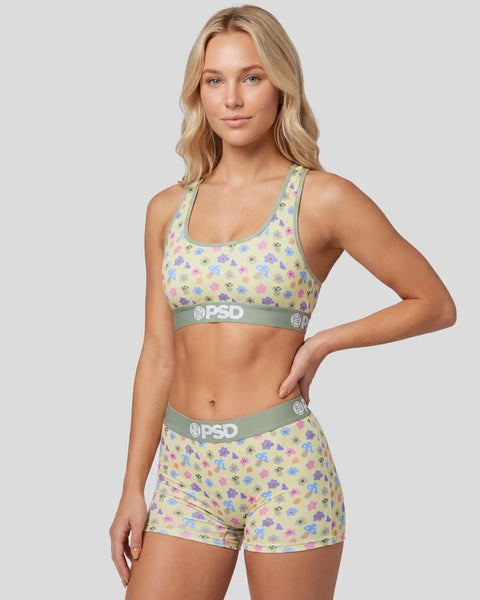 Woman wearing yellow sports bra and shorts with multicolored mushroom print and gray PSD waistbands.