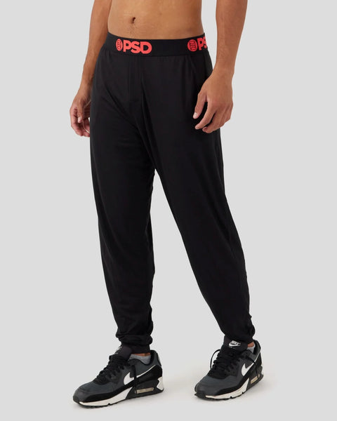 Black lounge pants with red PSD waistband, tapered leg fit, shown on male model.