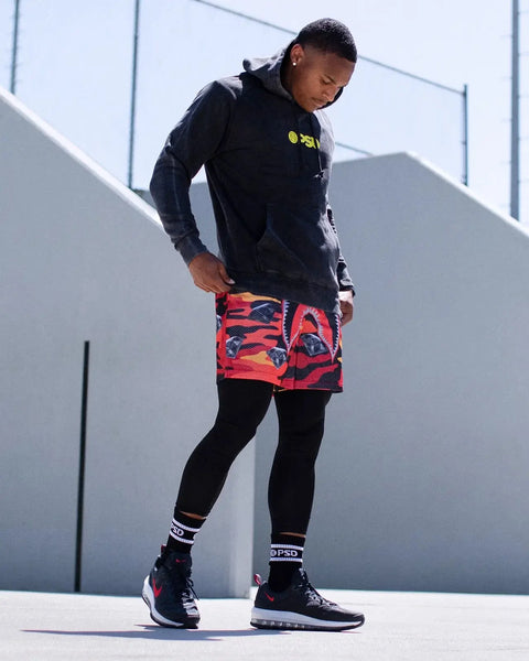 Black 3/4 length fitted tights worn with colorful patterned shorts and athletic shoes.