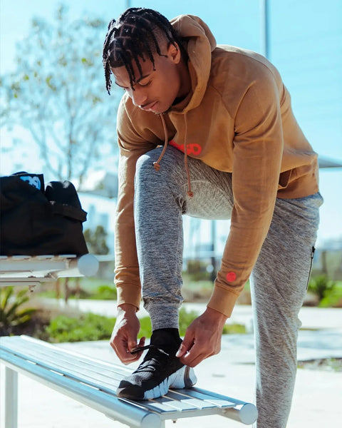 Grey heathered joggers with tapered cuffs worn by model bending forward outdoors.