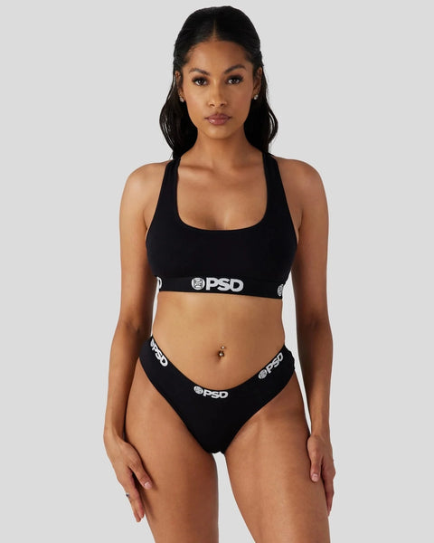 Woman wearing black sports bra and matching briefs with PSD branding on waistbands.