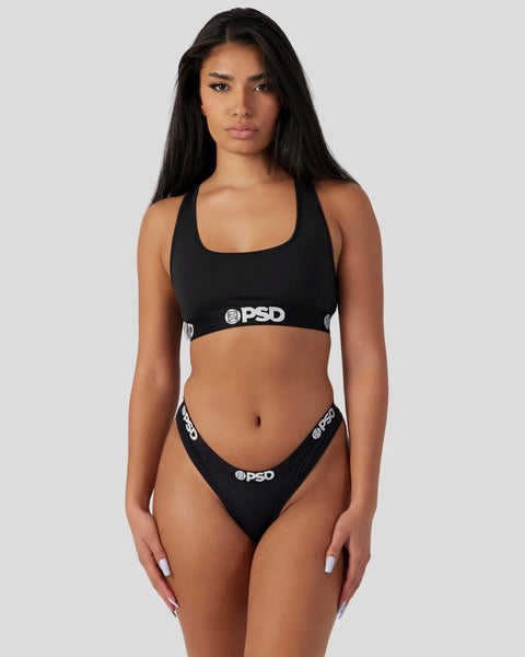 Black racerback sports bra and thong bikini bottom set with PSD branding.